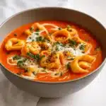 creamy tomato tortellini soup in bowl with basil and Parmesan