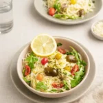 A large bowl of Cold Lemon Capellini Salad With Arugula on a wooden table