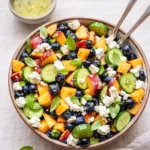 A fresh and colorful Blueberry Peach Feta Salad in a white bowl.