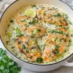 Golden-brown Creamy Coconut Lime Chicken in a skillet with lime wedges.