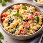 A large bowl of Creamy Italian Pasta Salad with fresh vegetables and salami