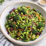A vibrant Broccoli Salad with purple cabbage and sesame seeds in a ceramic bowl.