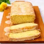 Freshly sliced Vegan Dandelion Bread on a wooden board with dandelion flowers.